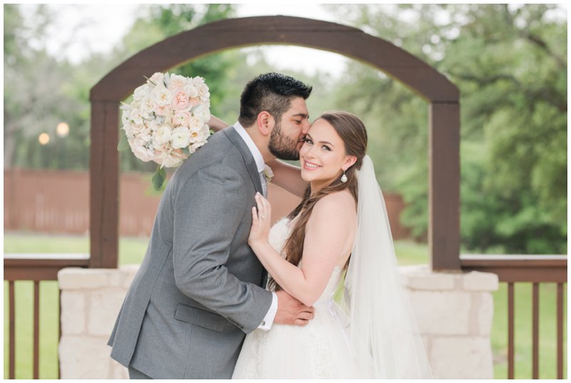 Groom kisses bride on cheek at blush wedding in Texas 