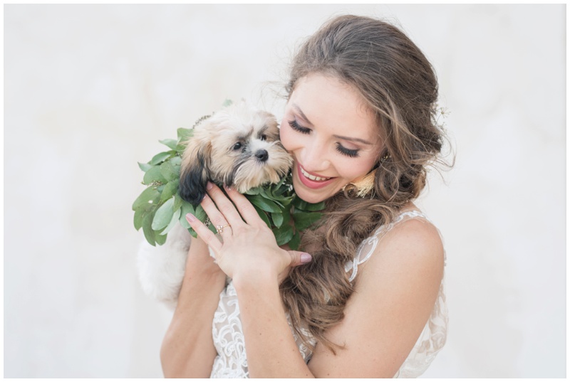 Bride snuggles puppy in flower collar at Villa Antonia in Austin