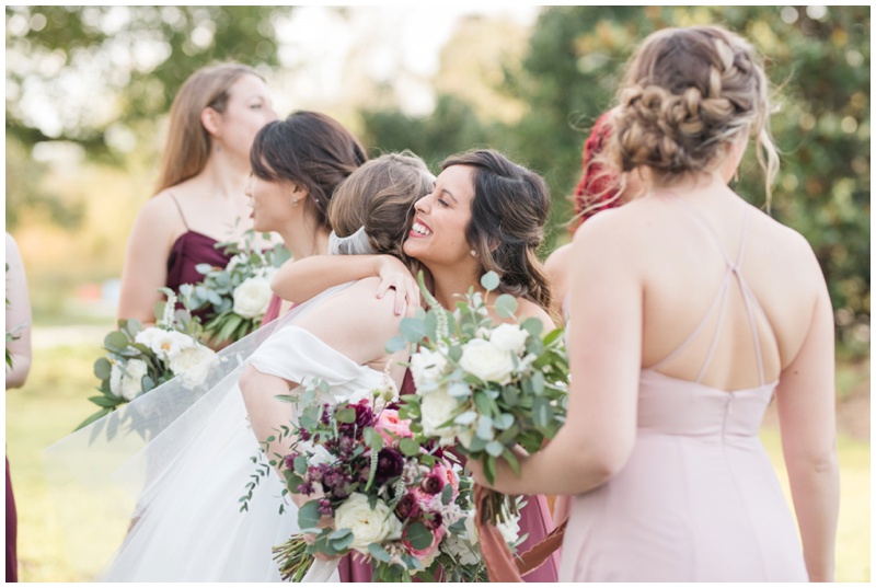 Candid moments of bride being hugged by her bridesmaids tribe immediately following her Barr Mansion Wedding ceremony in Austin