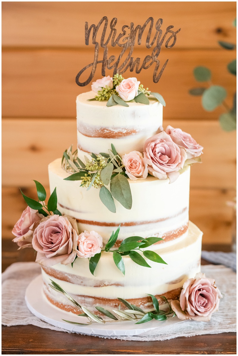 Naked wedding cake with vintage roses and greenery topped with Mr and Mrs wooden cutout 