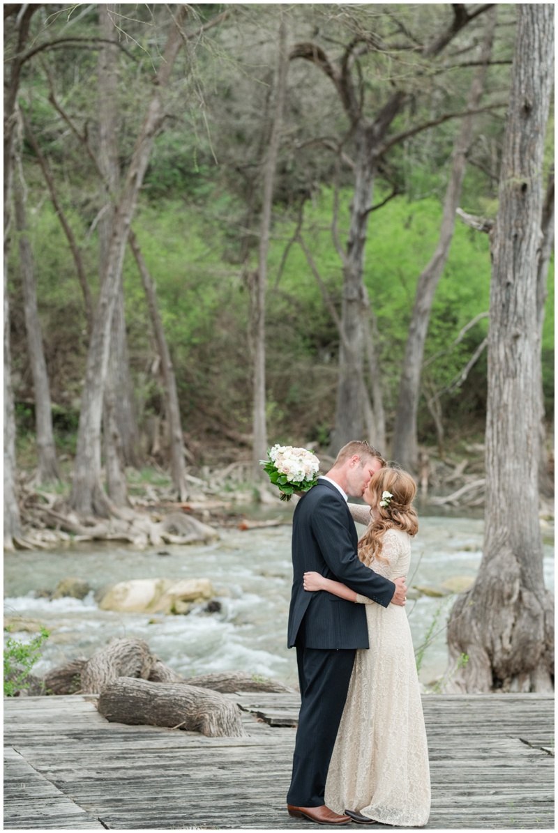 Bride and groom share a kiss by the river at their Wimberley Elopement ceremony