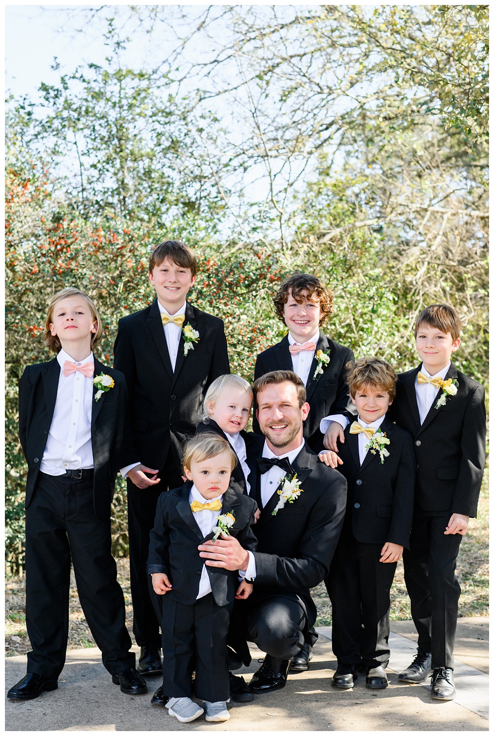 Groom surrounded by 6 ring bearers in yellow and pick bow ties at Marian Shrine of Our Lady of Schoenstatt in Austin Texas