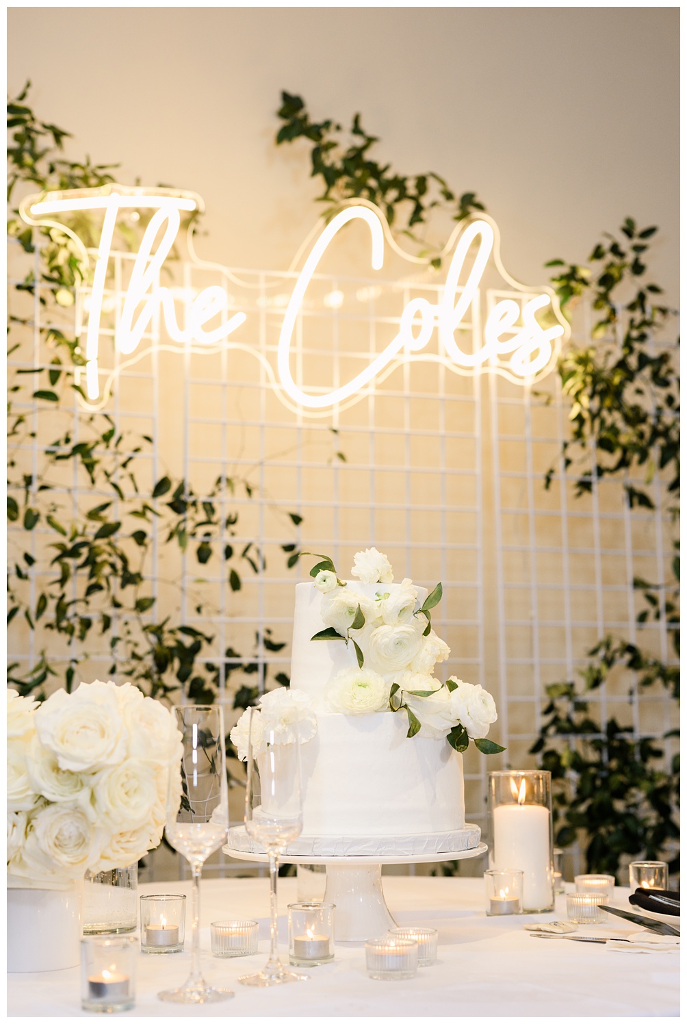 Wedding cake with neon sign of new last name behind it