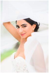 Close-up of a bride smiling softly while lifting her veil overhead during a natural light bridal portrait session in Austin, TX.