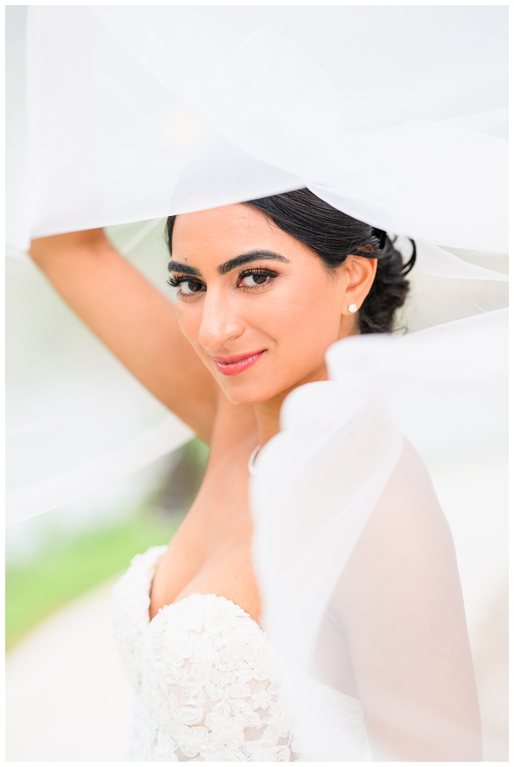 Close-up of a bride smiling softly while lifting her veil overhead during a natural light bridal portrait session in Austin, TX.